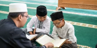 Seorang Guru sedang Mengajar Membaca Al-Qur'an ke Dua Orang Anak