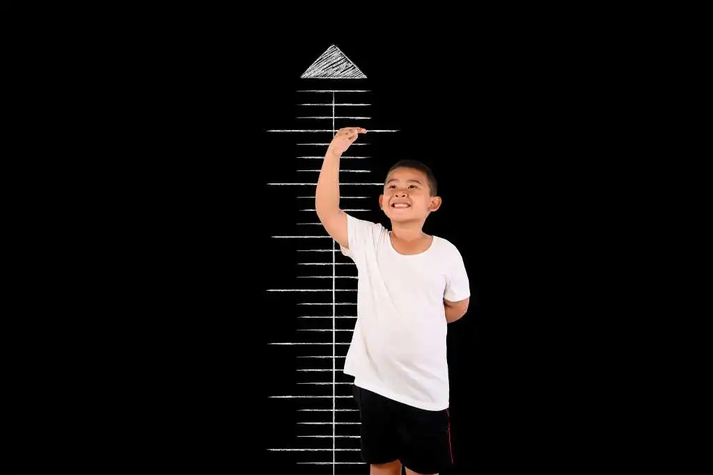Seorang anak sedang mengukur tingginya menggunakan papan tinggi badan